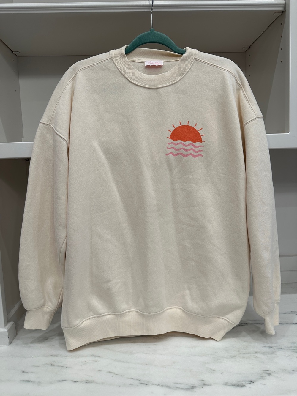 Pink Lily small cream sweatshirt.  Seas The Day logo on back. Like new